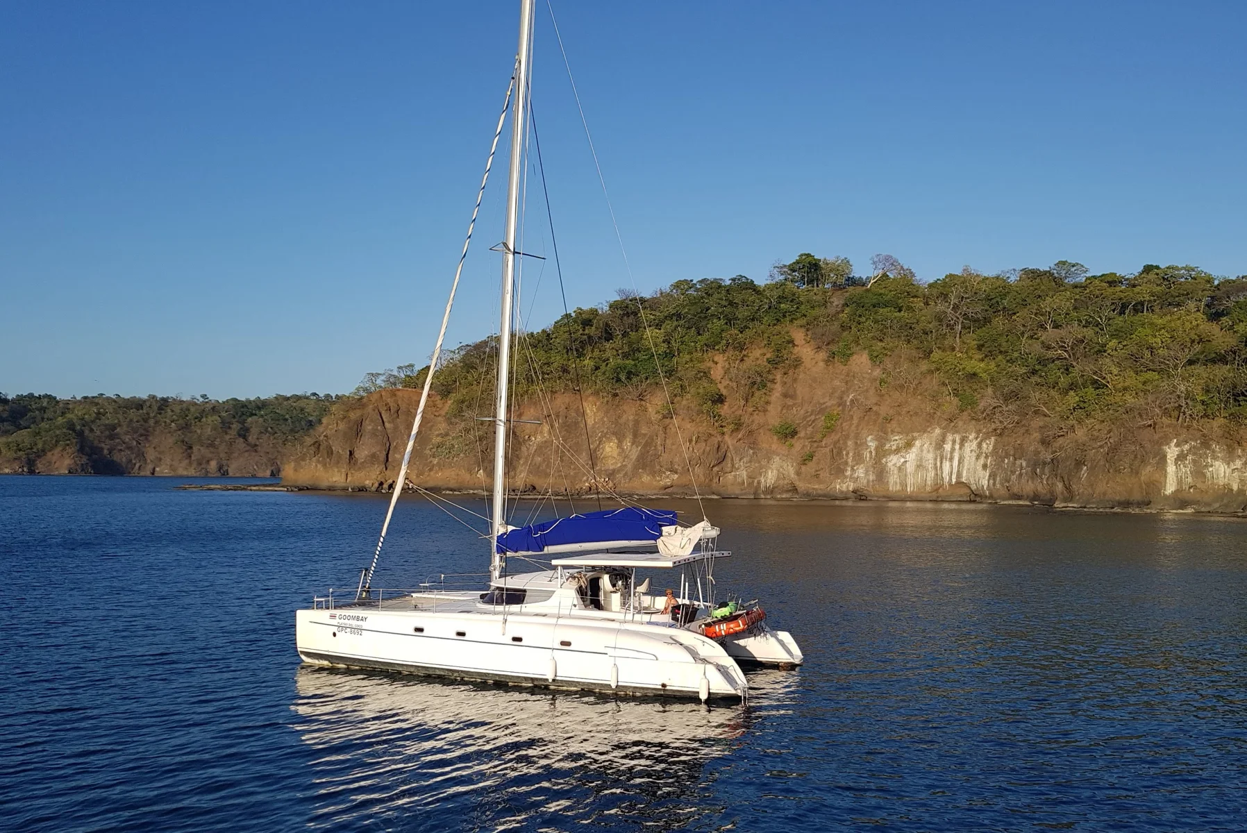 White catamaran sailing on calm blue water along the Pacific coast